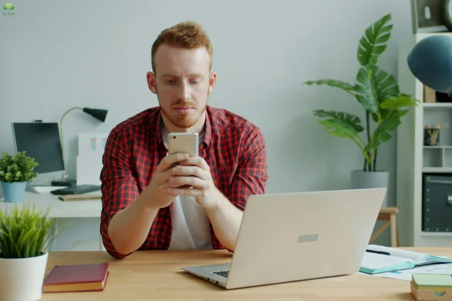 Standing Desk setup with a man using his phone in a modern workspace.